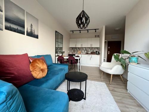 a living room with a blue couch and a kitchen at TS New Town Top Apartment in Szczecin