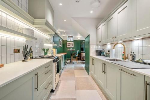 uma grande cozinha com armários brancos e paredes verdes em Luxury Mews House in Harrogate em Harrogate