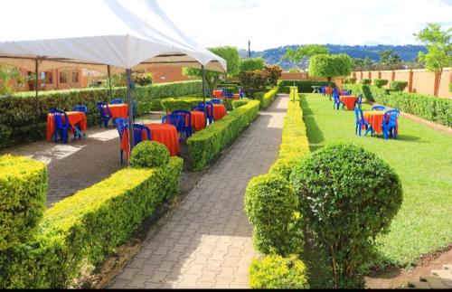 PRIMEROSE HOTEL في Mubende: صف من الطاولات والكراسي الملونة في الحديقة