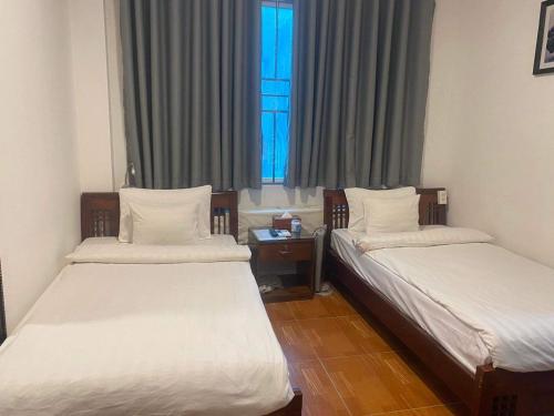 two beds in a room with a window at A25 Hotel - Đội Cấn 2 in Hanoi