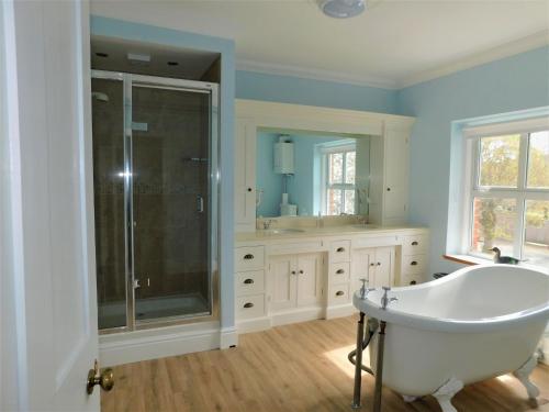 a bathroom with a tub and a glass shower at Corner House in Sheringham