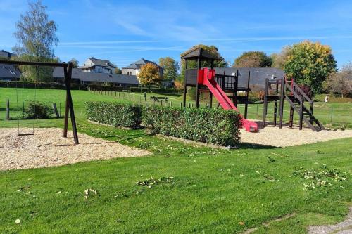 a playground in a park with a red slide at Sous le Charme - Gîte rural grande capacité (16p) in Herbeumont