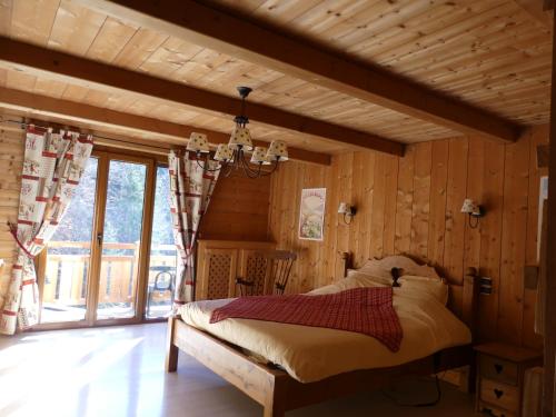 1 dormitorio con 1 cama en una habitación con paredes de madera en Auberge des églantiers, en Flumet