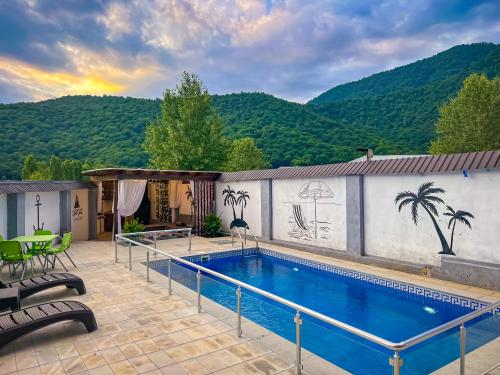 a swimming pool on a house with a mountain in the background at Qafqaz Mountain Chalet in Gabala