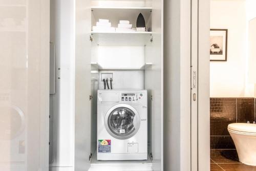 a washer and dryer in a bathroom with a toilet at Financial District w WD gym elevator NYC-1360 in New York