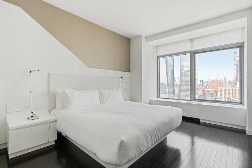 a white bedroom with a large bed and a window at Financial District w WD gym elevator NYC-1366 in New York