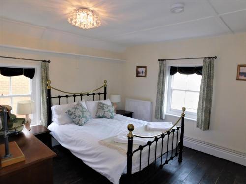 a bedroom with a bed and a table and two windows at Clarendon in Sheringham