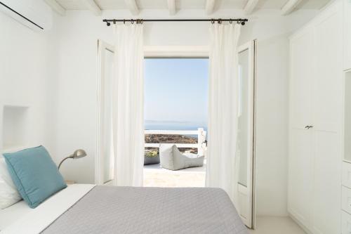 una camera da letto bianca con vista sull'oceano di Villa Crystal by Mykonos Mood a Fanari