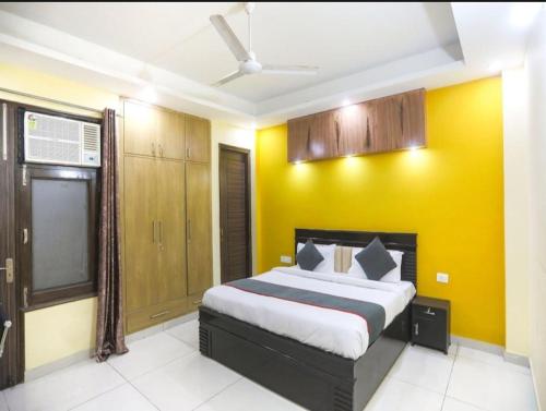 a bedroom with a bed with a yellow wall at Hotel Logix in Noida