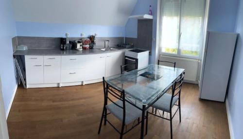 eine Küche mit einem Glastisch, Stühlen und einer Theke in der Unterkunft Gite for You Orchidée in Neuvy-sur-Loire