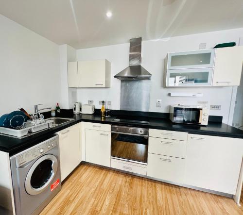 a kitchen with white cabinets and a sink and a dishwasher at Modern Canary studio- Wifi in London