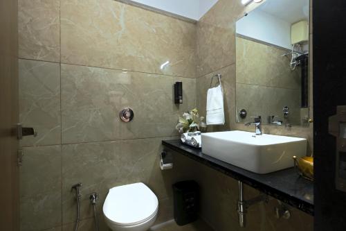 uma casa de banho com um lavatório, um WC e um espelho. em Axon Aleta em Mumbai