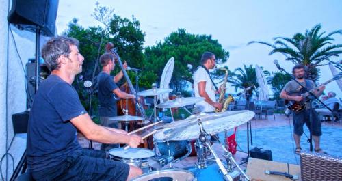 Un groupe de gens jouant du tambour à une fête dans l'établissement Les villas de Bagheera, oasis naturiste, à Linguizzetta