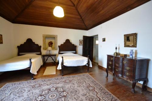 
a hotel room with a bed, chair, table and lamps at Casa dos Assentos de Quintiaes in Quintiães
