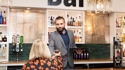 a man standing at a bar holding a glass of wine at Bank House Pitlochry in Pitlochry