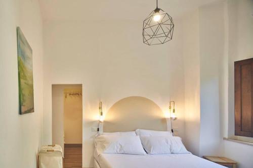 ein Schlafzimmer mit einem weißen Bett und einer Hängeleuchte in der Unterkunft Il Leccio Country House in Siena