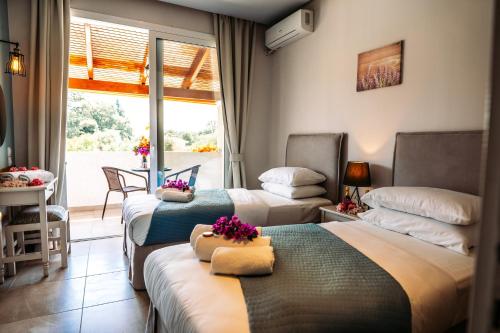 um quarto de hotel com três camas e uma varanda em The Flower Garden em Ýpsos