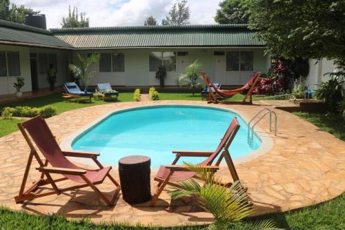 einen Pool mit zwei Gartenstühlen und ein paar Stühlen in der Unterkunft Karanga River Lodge in Moshi
