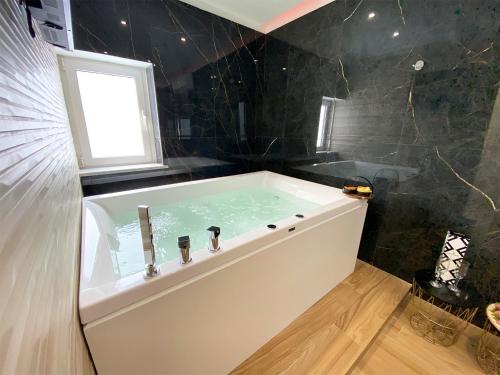 a large bath tub in a bathroom with black tiles at Dimora Sicula Relais - Palermo in Palermo