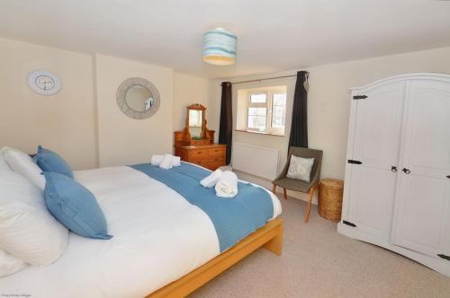 une chambre avec un grand lit avec des oreillers bleus et blancs dans l'établissement Compass Rose Cottage, à Sheringham