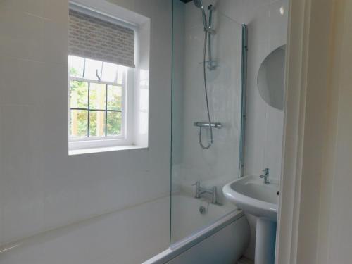 a white bathroom with a shower and a sink at Little Lodge in Sheringham