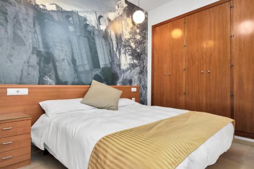 a bedroom with a bed and a painting on the wall at GAV La Ermita in Ronda