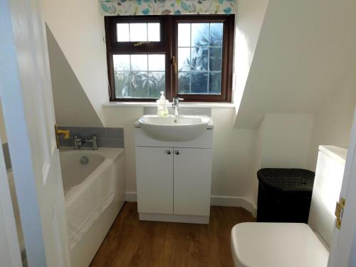 ein Badezimmer mit einem Waschbecken, einer Badewanne und einem WC in der Unterkunft 23 Chapel Street in Northrepps