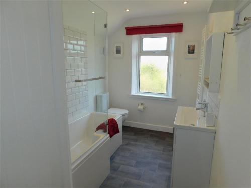 a bathroom with a tub and a toilet and a sink at Repton Cottage in West Runton