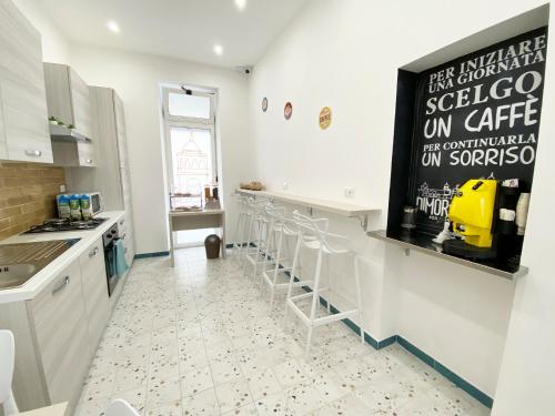 a kitchen with white counters and stools at Dimora Sicula Relais - Palermo in Palermo