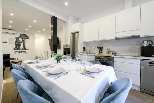 un comedor con una mesa blanca y sillas azules en Palacio Real DownTown,by MONARO*****, en Madrid