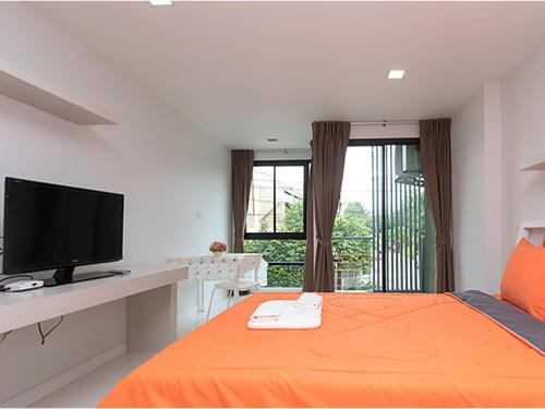 1 dormitorio con 1 cama, TV y balcón en Peaberry Place - พีเบอร์รี่เพลส en Ban Song Krathiam