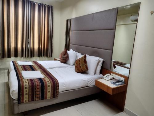 Empire Hotel - Grant Road في مومباي: غرفة الفندق بسرير ومرآة