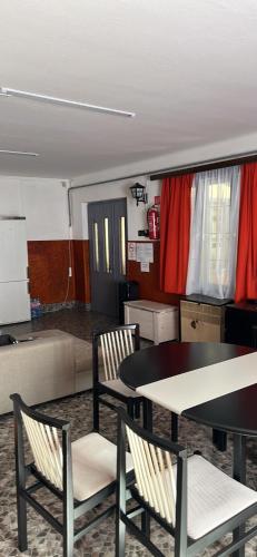 Habitación con 2 sillas, mesa y cortinas rojas en Lala-Lak, en Kisújszállás