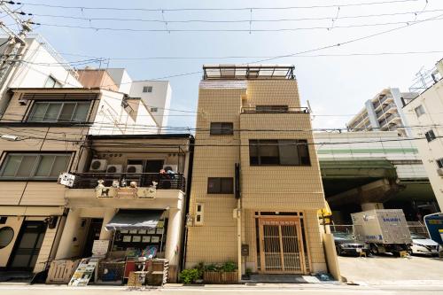 een hoog gebouw met mensen op een balkon bij 大阪道顿堀 铁甲猫の家 in Osaka