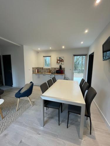 une salle à manger avec une table et des chaises blanches dans l'établissement Les Chalets du Mancel - Chalet Victor - 500 m Bouleries Jump , 10 min du circuit des 24h, à Parence