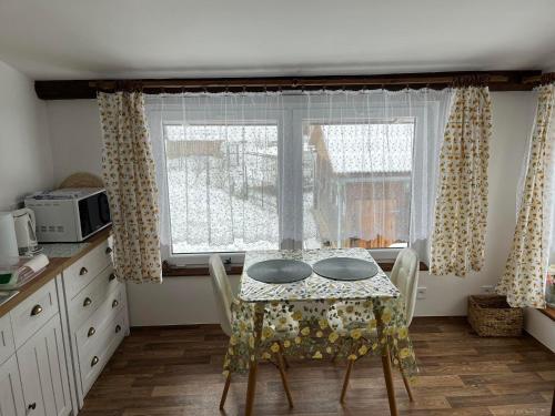 a table and chairs in a kitchen with a window at Chalupa Vojtěchov in Hvozd