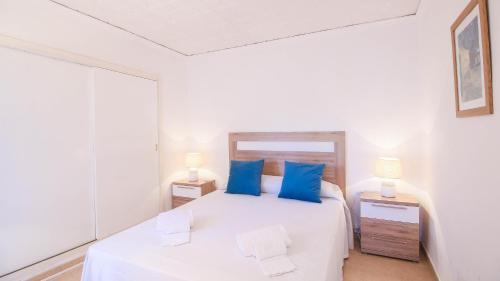 a bedroom with a white bed with blue pillows at Las Meninas in Denia