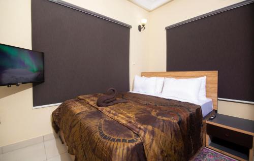 a hotel room with a bed and a flat screen tv at ChallawaRiver Homes in Calabar