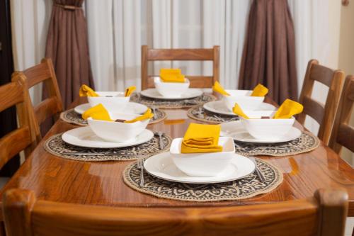 una mesa de madera con cuencos blancos y servilletas amarillas. en ChallawaRiver Homes, en Calabar