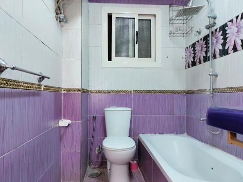 ein lila Badezimmer mit einem WC und einer Badewanne in der Unterkunft Maadi ring road Family apartment in Kairo