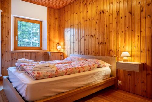 ein Schlafzimmer mit einem Bett in einer Holzwand in der Unterkunft Villa la Brisa 2 in Predazzo