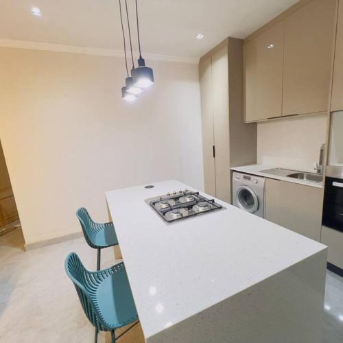 a kitchen with a white counter and blue chairs at Cosy 2 bed house w power backup in Sandton