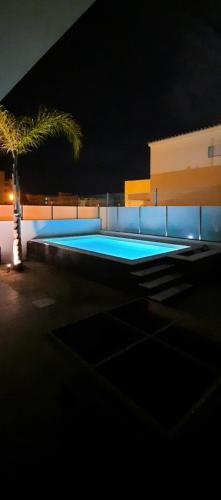 a swimming pool at night with a palm tree at Lovely Home, WIFI, Jardim in Armação de Pêra