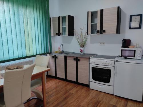 a kitchen with white appliances and a table with chairs at Diva Apartments in Satu Mare