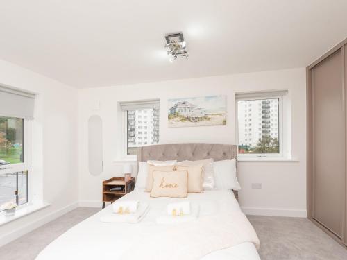 a white bedroom with a large white bed with windows at Pass the Keys Modern Haven with Juliet Balcony in Leeds