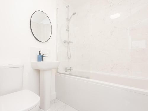 uma casa de banho branca com um lavatório e um espelho em Pass the Keys Modern Haven with Juliet Balcony em Leeds