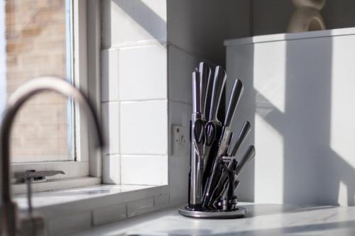 eine Küchentheke mit Messern in einem Halter neben einer Spüle in der Unterkunft The Camden Road Collection in London