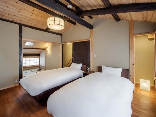 Duas camas num quarto com tectos em madeira em Sumire-an Machiya House em Quioto