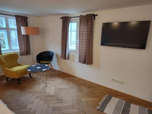 a living room with a chair and a television on the wall at Ferienwohnung RESL - geschmackvoll renoviert & zentral im historischen Schindelhaus in Oberstaufen