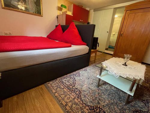 a bedroom with a bed with red pillows and a table at Ferienwohnung Amethyst in Burgberg